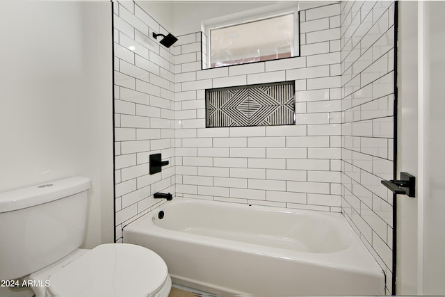 bathroom with toilet and tiled shower / bath