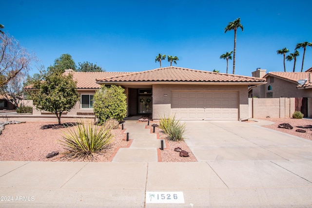 view of front of house with an attached garage, fence, a tile roof, stucco siding, and driveway