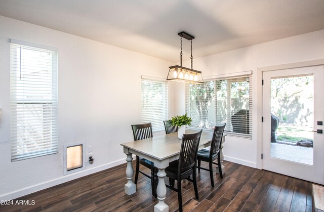 dining room with dark wood-type flooring, a wealth of natural light, and a notable chandelier