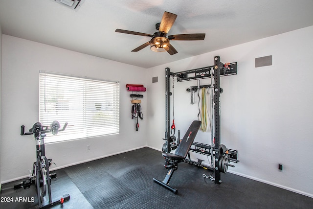 exercise room with dark carpet and ceiling fan