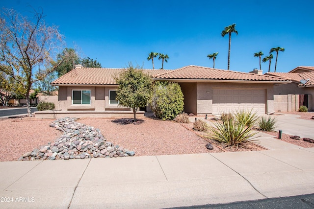 ranch-style house featuring a tiled roof, a chimney, driveway, and stucco siding