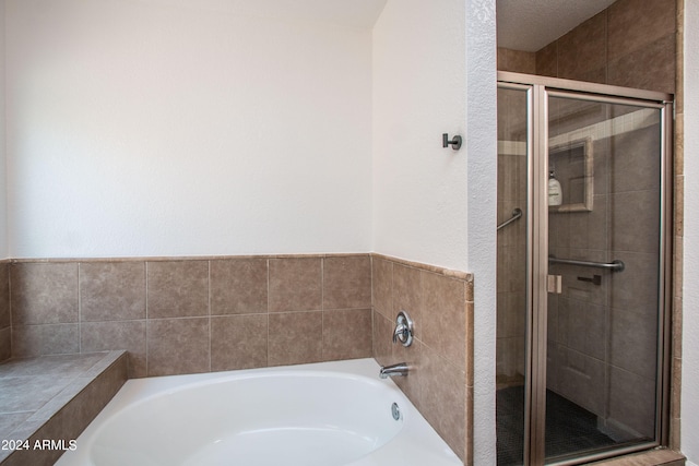 bathroom with independent shower and bath and a textured ceiling