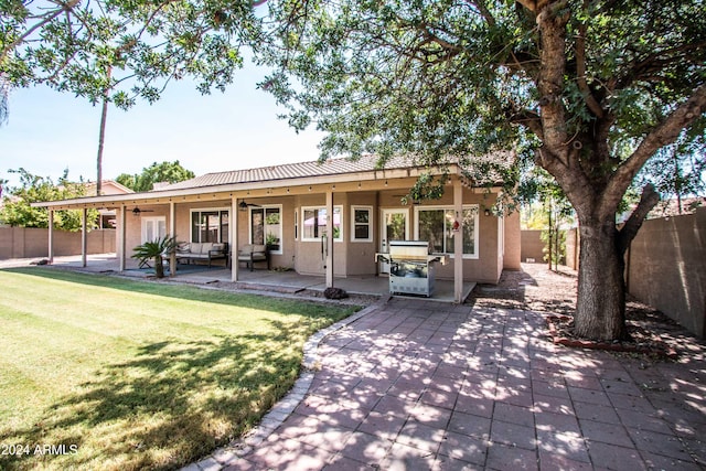 rear view of property with ceiling fan, a yard, and a patio area