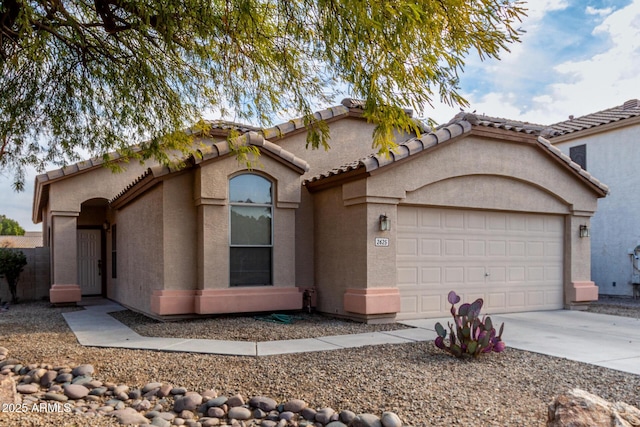 view of front of house with stucco siding, a garage, driveway, and a tile roof