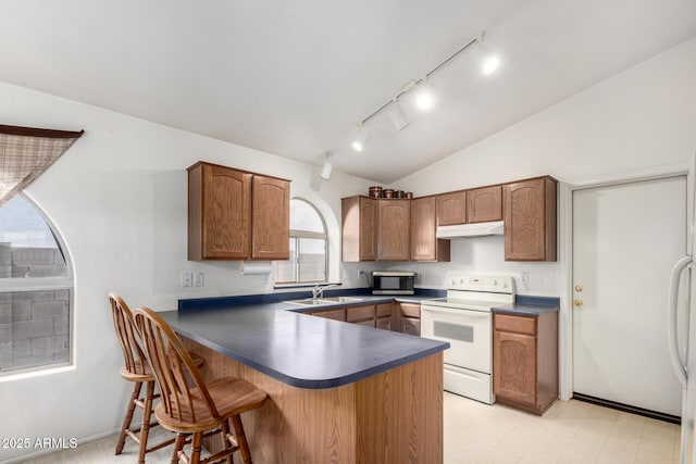 kitchen with white electric range, stainless steel microwave, under cabinet range hood, dark countertops, and vaulted ceiling