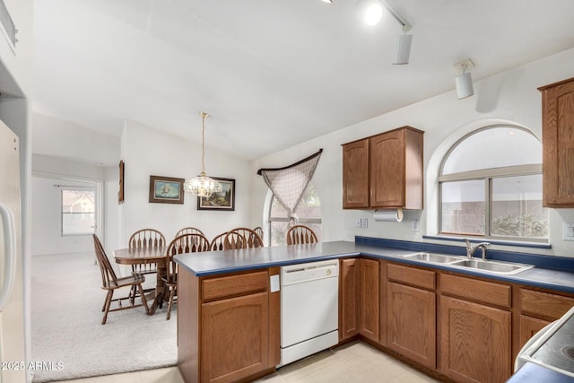 kitchen with decorative light fixtures, dishwasher, vaulted ceiling, a peninsula, and a sink