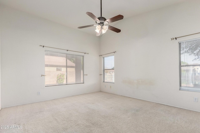 carpeted empty room with a high ceiling and a ceiling fan