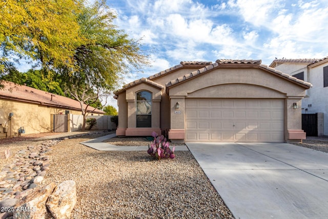 mediterranean / spanish-style home featuring fence, a garage, driveway, and stucco siding