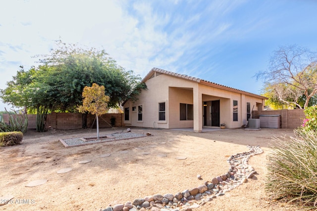 back of property with a tiled roof, stucco siding, cooling unit, a fenced backyard, and a patio