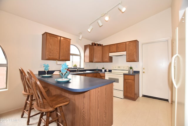 kitchen with white range with electric cooktop, lofted ceiling, a peninsula, under cabinet range hood, and dark countertops