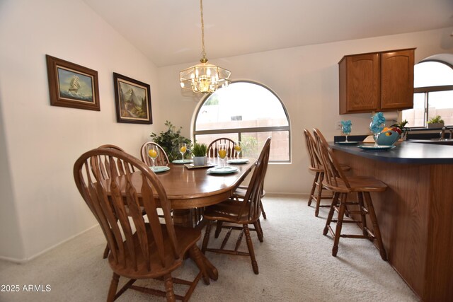 dining space featuring a notable chandelier, baseboards, light colored carpet, and vaulted ceiling