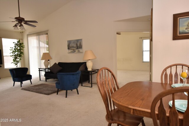 dining room featuring ceiling fan, high vaulted ceiling, and light carpet