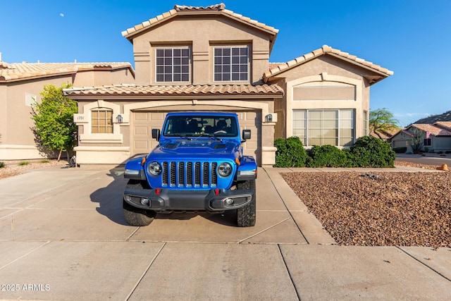 mediterranean / spanish home featuring concrete driveway, stucco siding, and a tile roof
