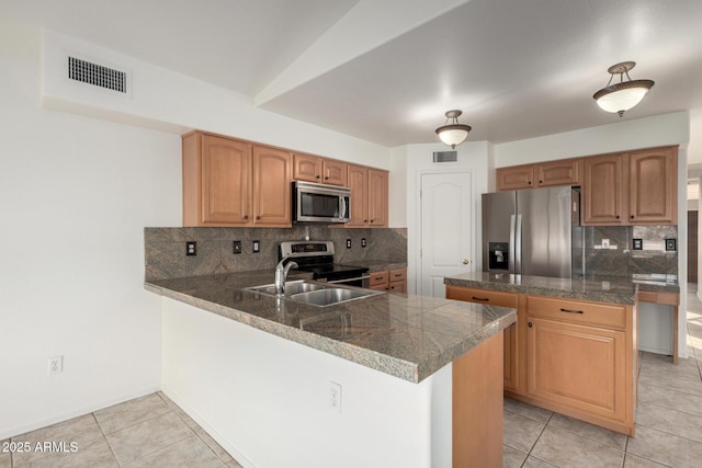 kitchen with a peninsula, visible vents, appliances with stainless steel finishes, a sink, and tile counters