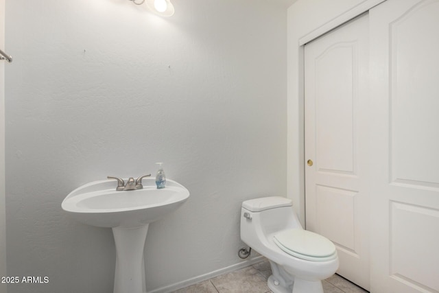 half bath featuring tile patterned flooring, baseboards, and toilet