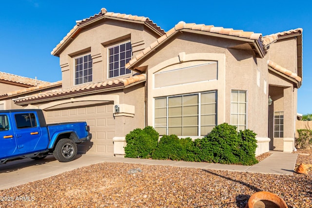 view of front of home with a tiled roof, driveway, stucco siding, and a garage
