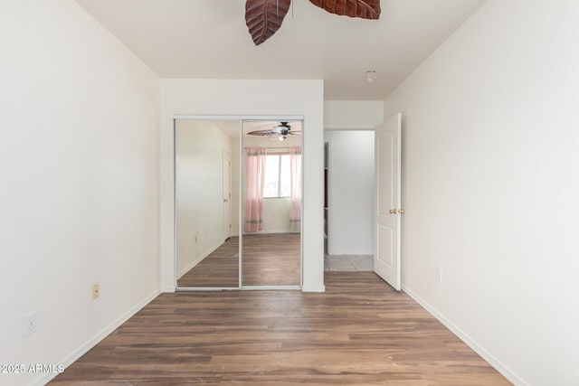 unfurnished bedroom with wood finished floors, baseboards, and a ceiling fan