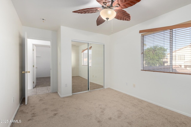 unfurnished bedroom featuring a closet, baseboards, ceiling fan, and carpet