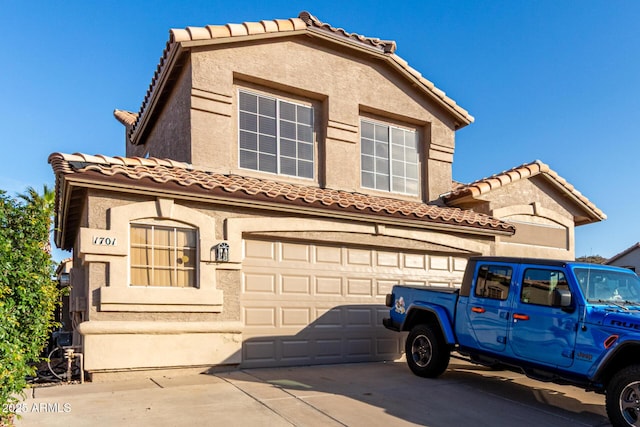 mediterranean / spanish house featuring an attached garage, driveway, a tiled roof, and stucco siding