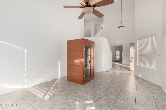 empty room with light tile patterned floors, a towering ceiling, and a ceiling fan