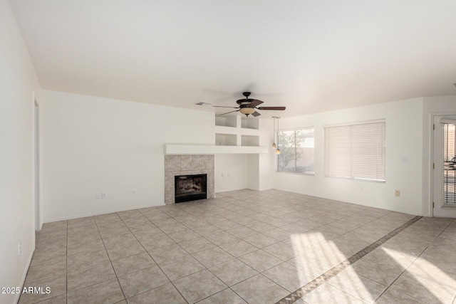 unfurnished living room featuring a tiled fireplace and a ceiling fan