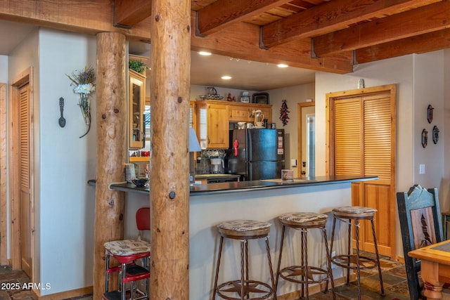 kitchen with beamed ceiling, black refrigerator, a breakfast bar, and kitchen peninsula