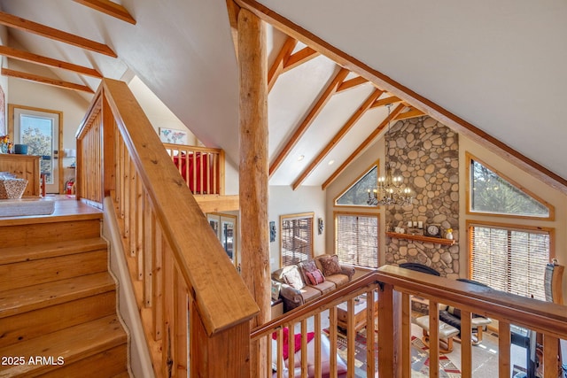 stairs with beamed ceiling, high vaulted ceiling, a healthy amount of sunlight, and a fireplace