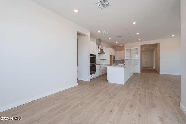 1254 E Penedes Dr, Gilbert, AZ 85298 - kitchen featuring wall chimney exhaust hood, open floor plan, white cabinetry, baseboards, and decorative backsplash