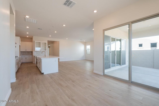 1254 E Penedes Dr, Gilbert, AZ 85298 - kitchen featuring open floor plan, white cabinetry, light countertops, light wood finished floors, and a kitchen island with sink