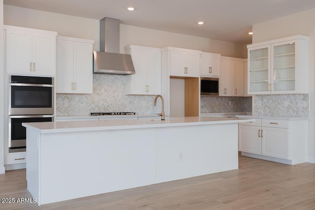 1254 E Penedes Dr, Gilbert, AZ 85298 - kitchen featuring wall chimney range hood, stainless steel double oven, a sink, stovetop, and a kitchen island with sink