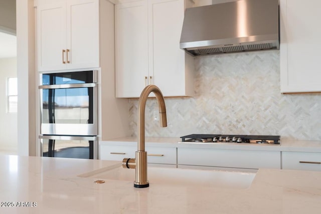 1254 E Penedes Dr, Gilbert, AZ 85298 - kitchen with wall chimney range hood, white cabinetry, tasteful backsplash, and light stone countertops