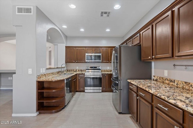 421 W Mountain Sage Dr, Phoenix, AZ 85045 - kitchen with stainless steel appliances, arched walkways, a sink, light stone counters, and recessed lighting