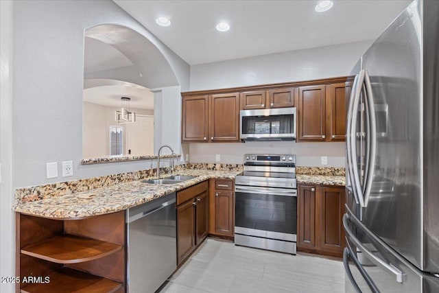 421 W Mountain Sage Dr, Phoenix, AZ 85045 - kitchen with appliances with stainless steel finishes, a sink, open shelves, light stone counters, and arched walkways