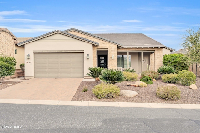 ranch-style home with a tile roof, decorative driveway, an attached garage, and stucco siding