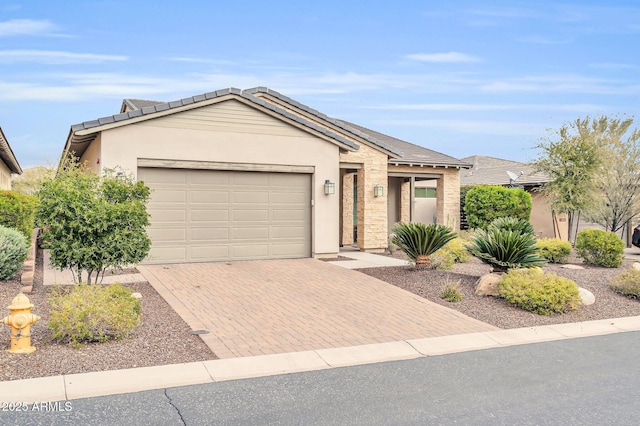 single story home with stone siding, stucco siding, decorative driveway, and a garage