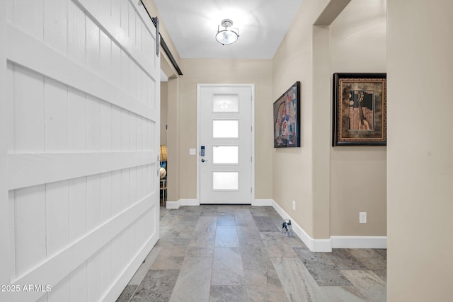 entryway featuring a barn door, baseboards, and stone finish floor