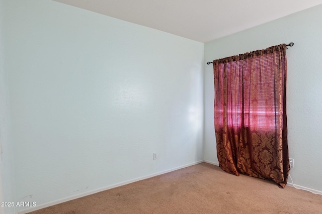 unfurnished room featuring light carpet and baseboards