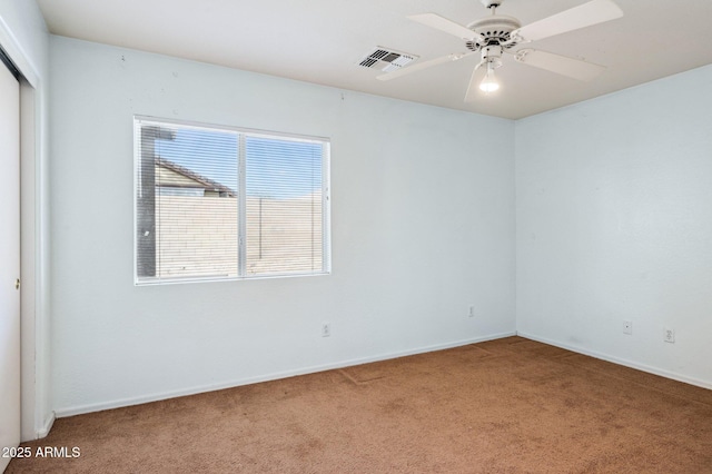 spare room featuring baseboards, carpet flooring, visible vents, and a ceiling fan