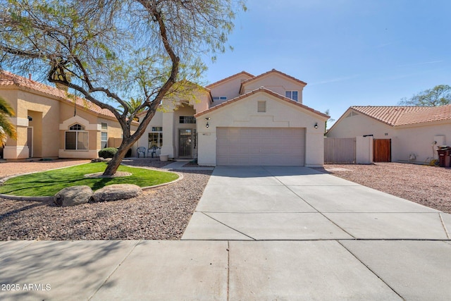 mediterranean / spanish-style home with an attached garage, fence, driveway, a tiled roof, and stucco siding