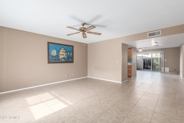 tiled empty room with ceiling fan and a textured ceiling