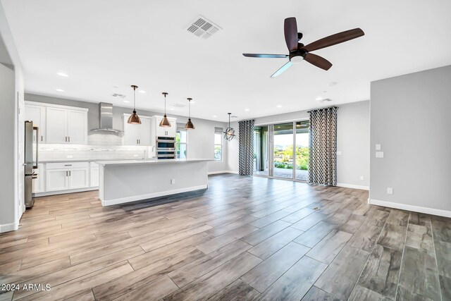 kitchen with light countertops, visible vents, backsplash, appliances with stainless steel finishes, and wall chimney range hood