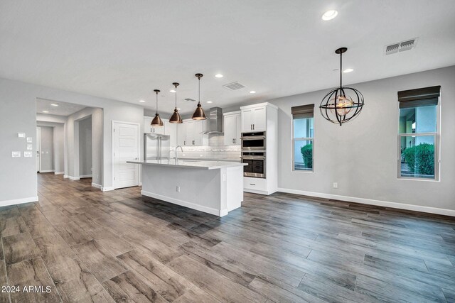 kitchen featuring dark wood finished floors, black electric stovetop, decorative backsplash, wall chimney exhaust hood, and stainless steel refrigerator