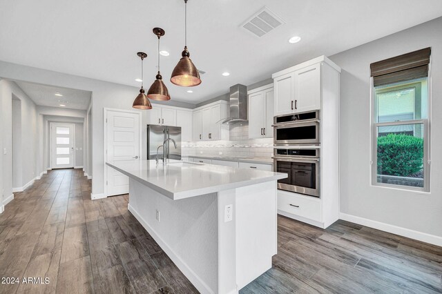 kitchen with black electric stovetop, light countertops, double oven, a sink, and wall chimney range hood