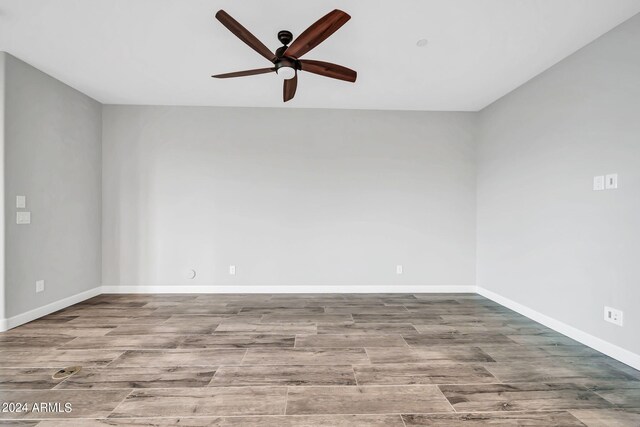 spare room featuring dark wood-type flooring, plenty of natural light, a ceiling fan, and baseboards