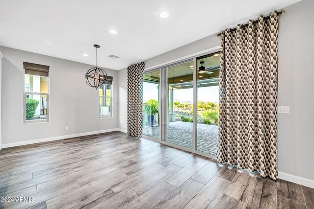 empty room with dark wood-style flooring, visible vents, and baseboards