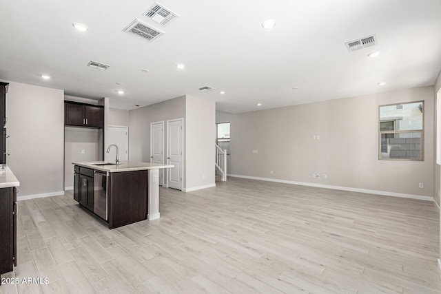 9366 E Sequence Ave, Mesa, AZ 85212 - kitchen with light wood-type flooring, a center island with sink, dishwasher, dark brown cabinetry, and light countertops