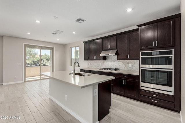 9366 E Sequence Ave, Mesa, AZ 85212 - kitchen featuring stainless steel appliances, under cabinet range hood, light wood-type flooring, a kitchen island with sink, and light countertops