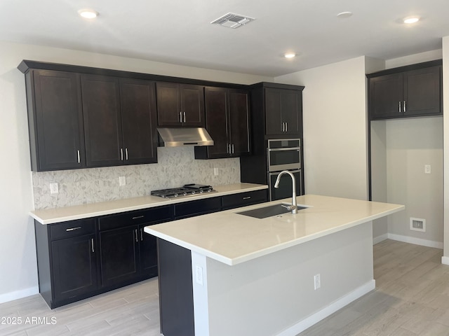 9366 E Sequence Ave, Mesa, AZ 85212 - kitchen with under cabinet range hood, appliances with stainless steel finishes, light wood-type flooring, backsplash, and recessed lighting