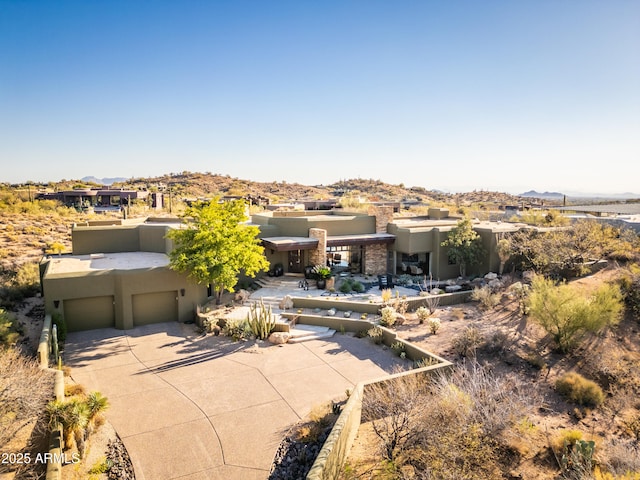 southwest-style home with a garage, concrete driveway, and stucco siding