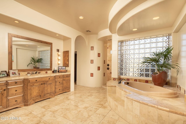 bathroom with vanity and tiled bath